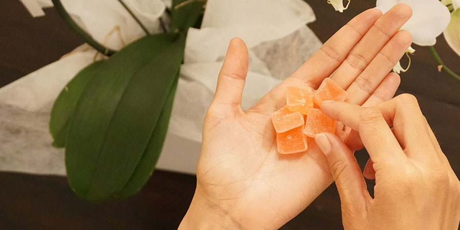 close up view of a person's hands holding orange gummies
